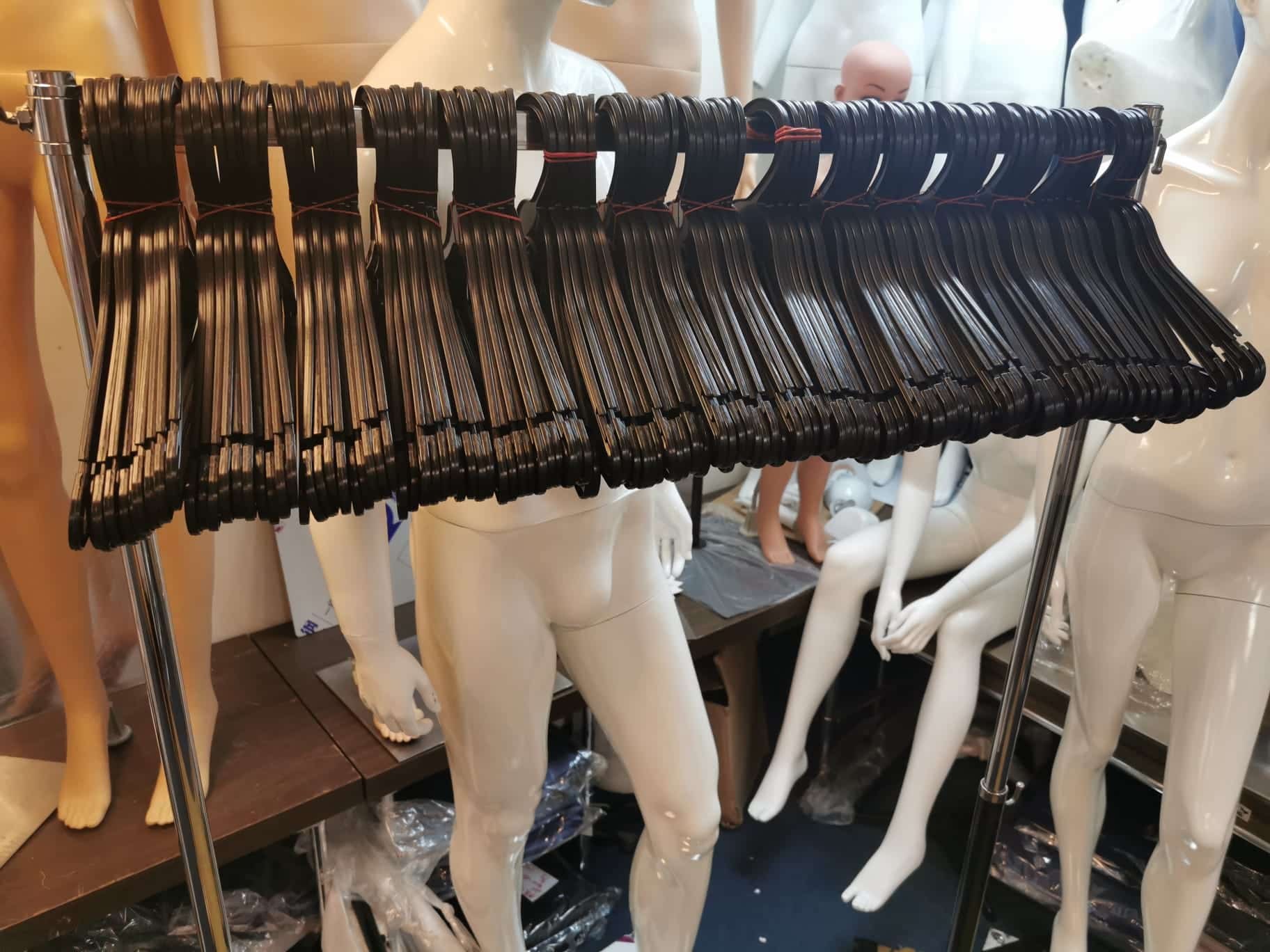 Black clothes hangers hanging from a rail
