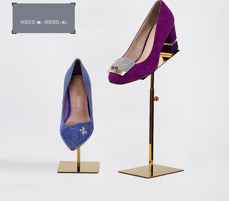 Two gold mirror shoe stands on a white background, one tall and one short, each holding a court shoe tilted forward.