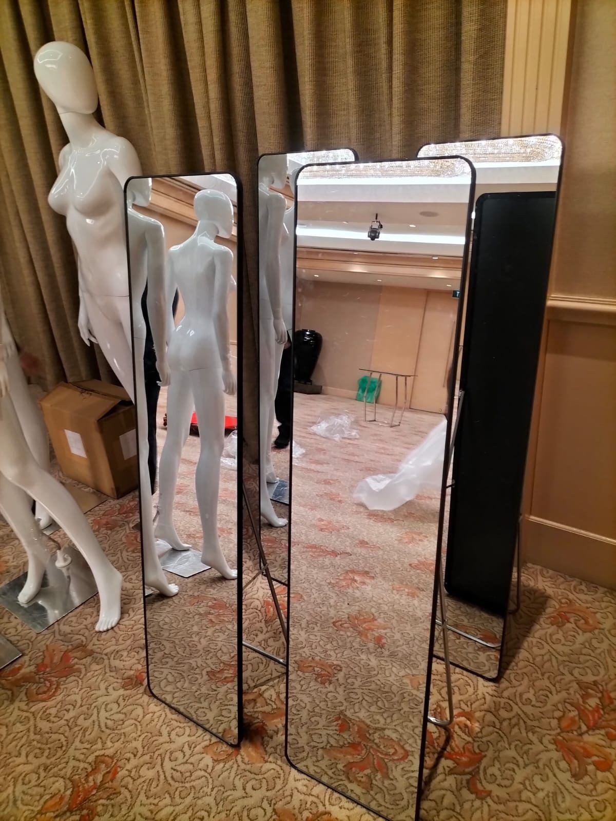 Standing mirrors with rounded rectangular frames beside mannequins