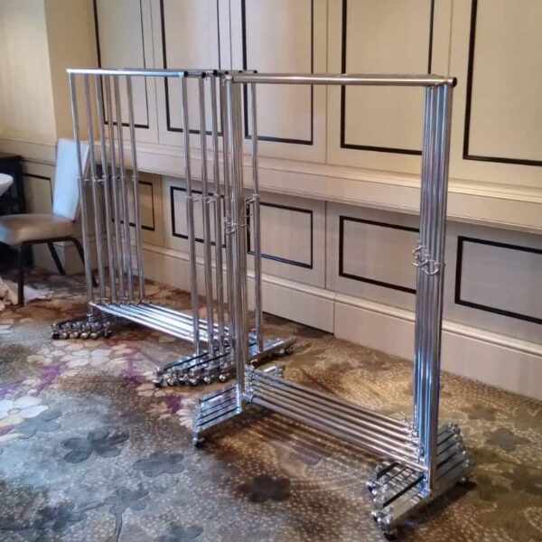 Rental clothes rack, silver chrome with wheel in the middle of the room.
