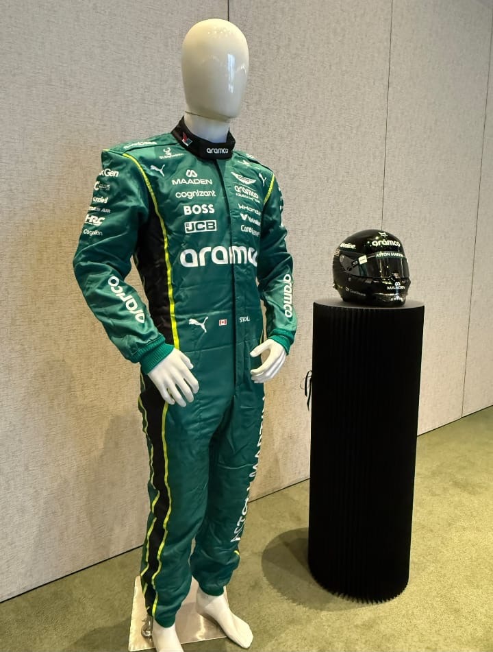 White faceless male full-body mannequin wearing a green racing suit beside a helmet display